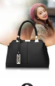 Detail of black lychee leather handbag featuring gold metal handles and a leaf pendant