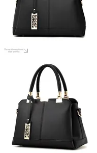 Detail view of black lychee leather handbag side and gold hardware with镂空 leaf pendant