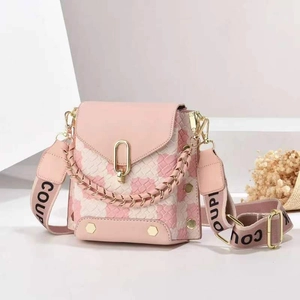 Pink checkered crossbody bag with gold hardware and wide woven strap on a white background