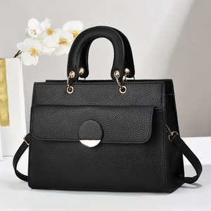 Close-up of black lychee grain leather handbag with gold clasp and shoulder strap