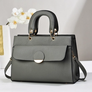 Detail of grey lychee texture handbag with gold hardware and trapezoid design
