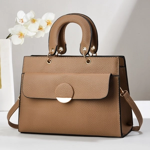 Detail of dark camel tote bag with lychee texture and circular gold metal buckle