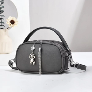 Detail of dark gray lychee leather bag with triple zippers and charm tassel