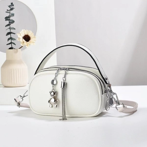 Modern white round crossbody bag with litchi grain leather and cute bear charm pendant