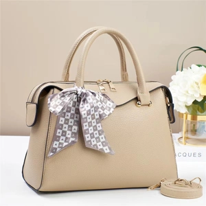Detail of beige litchi grain leather bag with heart print scarf and golden hardware