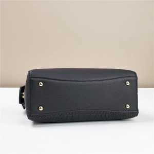 Detailed bottom view of black lychee grain bucket bag with gold metal feet and croc trim