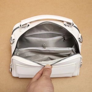 Detail showing the spacious interior of a white tote bag with multiple zipped compartments