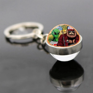 Detailed close-up of glass orb keychain with colorful Bigfoot and Alien illustration