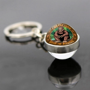 Macro shot of Bigfoot glass dome keychain with I Never Look Good In Photos text