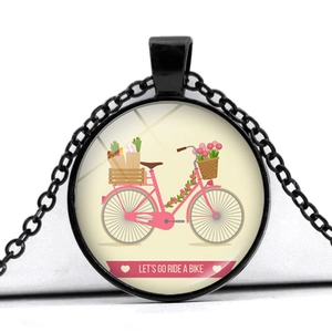 Close-up of vintage pink bicycle illustration in a black circular glass pendant