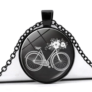 Macro detail of a vintage bicycle and flower pendant with black chain on white base