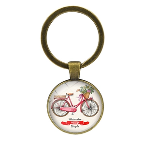 Detail of vintage bronze keychain featuring a watercolor bicycle under glass cabochon