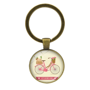 Detailed close-up of vintage bronze keychain with pink bicycle glass dome charm
