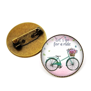 Détail d'une broche vélo vintage montrant le dôme en verre et l'épingle en métal bronze