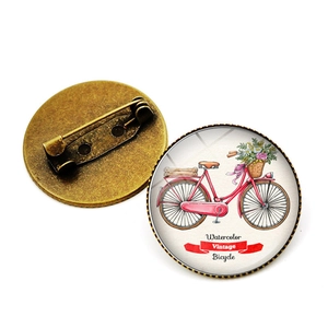 Vue détaillée d'une broche vélo vintage ronde avec panier fleuri et base en bronze vieilli