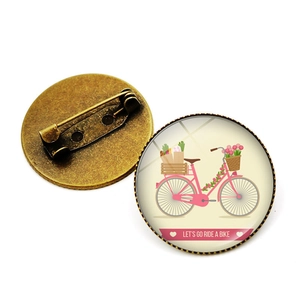 Détail de la broche vélo vintage montrant le dôme en verre et l'épingle de sûreté