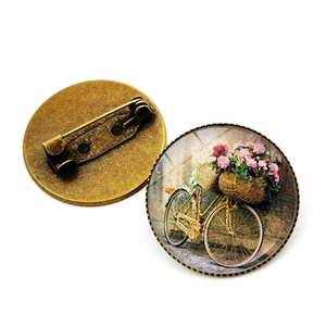 Gros plan de broches vintage vélo en verre avec finition bronze antique et épingles