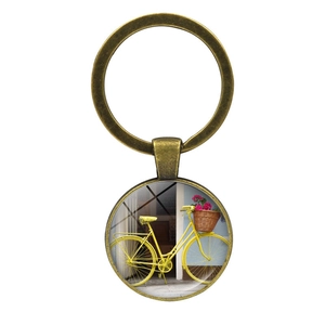 Vintage bronze bicycle key ring with floral basket pendant under a glass dome cabochon