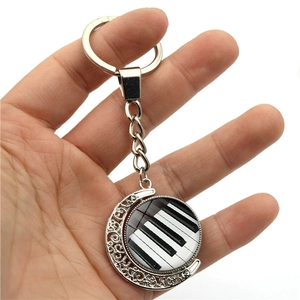 Detail of silver musical keychain with rotating piano keys glass dome in hand