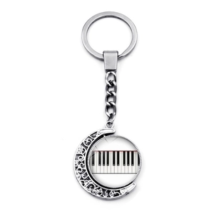 Detail of creative piano key keychain with crescent moon pendant in silver metal