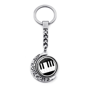 Detail of silver music keychain with rotating piano keys charm and hollow crescent frame