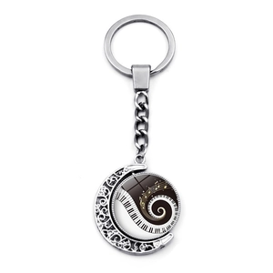 Detail of rotating keychain pendant with crescent moon base and piano key pattern