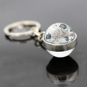 Detail of nautical keychain with vintage sea turtle and map design inside a glass ball