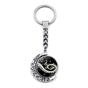 Rotating music keychain with piano keys and notes in silver crescent moon frame
