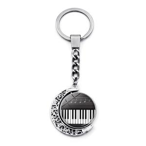 Silver musical keychain with crescent moon frame and rotating piano keys pendant