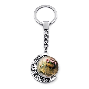 Detail of vintage silver crescent moon keychain with flower bicycle glass cabochon