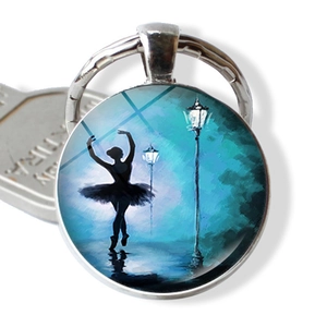Macro view of a ballerina silhouette glass dome keychain with artistic blue night painting
