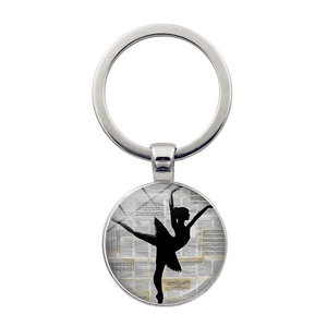 Dettaglio macro del portachiavi ballerina con sfondo di spartito musicale vintage