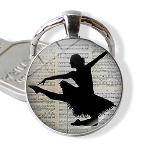 Close-up of ballet dancer silhouette keychain with vintage sheet music background