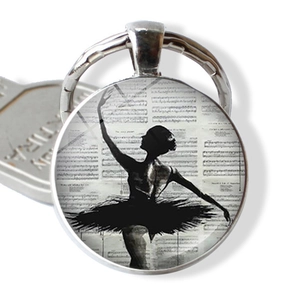 Detailed close-up of ballerina silhouette keychain with vintage musical score pattern