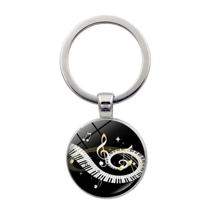 Macro view of a silver-toned musical glass dome keychain with piano keys and notes design