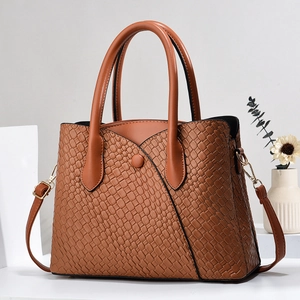 Close-up of brown tote bag featuring woven texture and gold metal buckle details