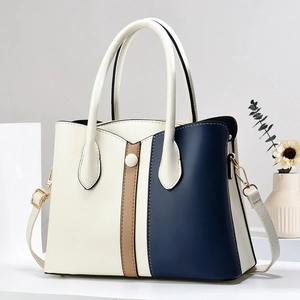 Detail of tricolor patchwork handbag in beige, brown and navy with gold metal hardware
