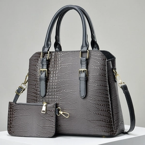 Gray crocodile pattern tote and pouch set with gold hardware on a white stand