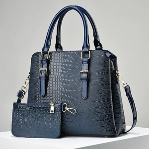 Detail of dark blue crocodile pattern tote bag with gold hardware and small pouch