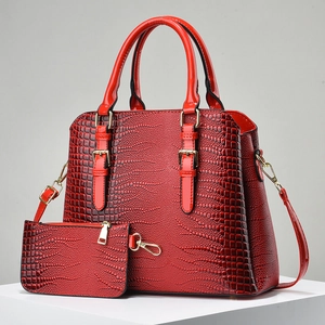 Detailed macro view of red crocodile-embossed two-piece handbag set with gold hardware