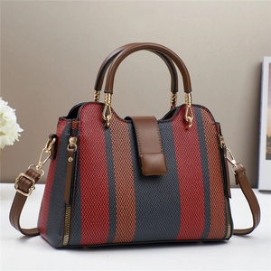 Détail du sac en toile rayé avec poignées en cuir marron et fermeture éclair dorée chic