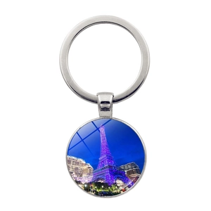 Close-up of silver keychain with a round glass pendant featuring the Eiffel Tower at night