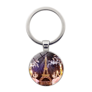 Detail of metal keychain with glowing Eiffel Tower night scene art under a glass dome