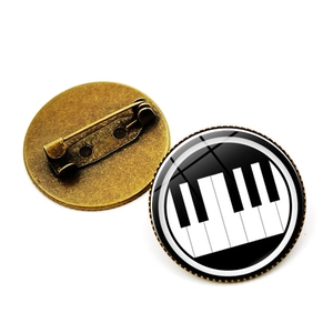 Dettaglio della spilla musicale rotonda con motivo a tastiera e retro in bronzo antico