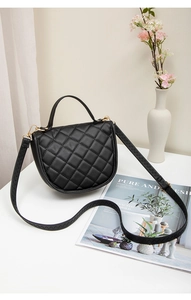 Detail view of black quilted faux leather crossbody bag with elegant gold hardware buckles