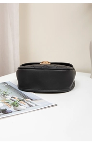 Close-up of black quilted leather shell bag showing steady bottom and gold metal lock