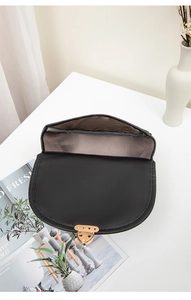 Internal view of a black quilted saddle bag with golden heart buckle and grey lining