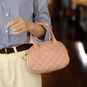 Pale pink quilted crossbody bag with golden logo and soft leather texture shown by model