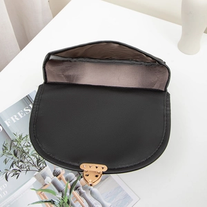 Schwarze matte Satteltasche aus Leder mit goldener Hardware und Stofffutter auf Tisch