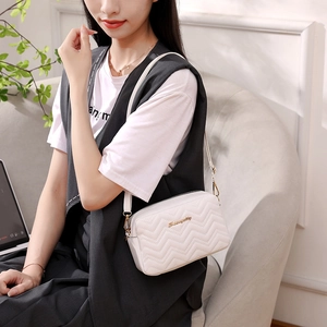 White wave-pattern quilted camera bag with gold logo and slim shoulder strap